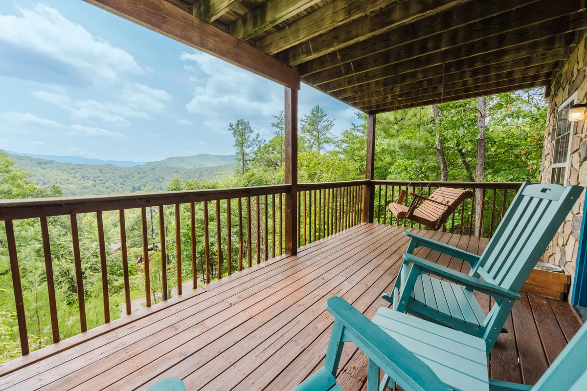 A peaceful wooden deck furnished with Adirondack chairs overlooks a breathtaking mountain view. Surrounded by lush woods, the deck invites guests to relax, read, or watch the sunrise and sunset. The tranquil natural setting is perfect for quiet moments or intimate conversations.