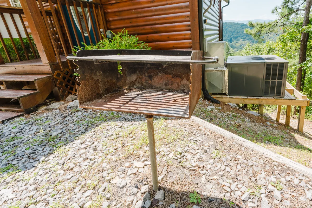 An inviting outdoor deck area with a charcoal grill surrounded by lush greenery. The setup is ideal for barbecuing, family gatherings, and alfresco dining in a relaxed, natural setting.