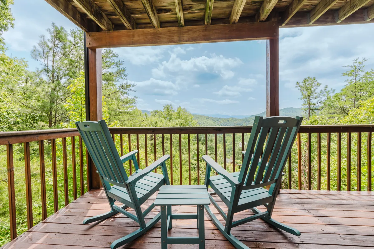 A peaceful porch scene with classic rocking chairs and a small table facing out towards a stunning mountain view. The tranquil setting is ideal for enjoying morning coffee, reading, or watching the sunrise.
